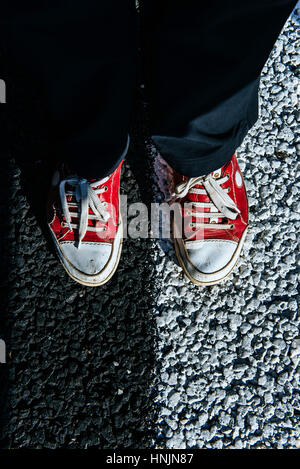 paar rote Schuh auf dem Bürgersteig. Schwarzer Asphalt Textur. Stockfoto