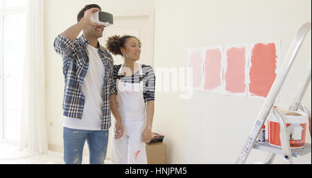 Paar nutzt virtual-Reality-Brille Malfarbe für Raum stehend Leiter wählen Stockfoto