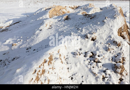 mit gelben Schnee Sand für Bauarbeiten bedeckt. Foto Nahaufnahme im Winter. Sonniges Wetter Stockfoto