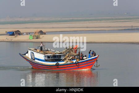 Ein hell gestrichenen Fluss bagger Boot unterwegs auf dem Irrawaddy Fluss in der Region Magway von Myanmar (Birma) mit saisonalen Hütte am Flussufer. Stockfoto