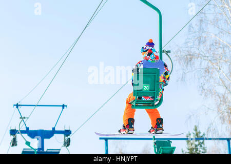 Snowboarder steigt auf dem Sessellift auf die Strecke. Stockfoto