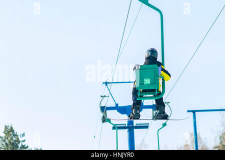 Snowboarder steigt auf dem Sessellift auf die Strecke. Stockfoto