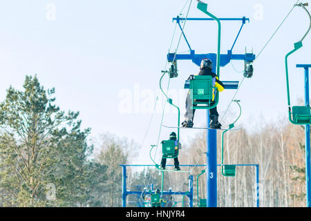 Snowboarder steigt auf dem Sessellift auf die Strecke. Stockfoto