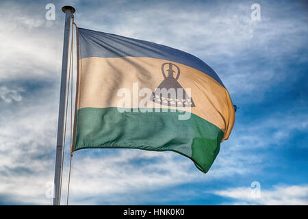 Bewegungsunschärfe in Lesotho winken Nationalflagge in den bewölkten Himmel Stockfoto