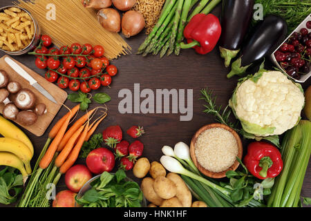 Foto von einer Tischplatte voll frisches Gemüse, Obst und andere gesunde Lebensmittel mit einem Leerzeichen in der Mitte für Text. Stockfoto