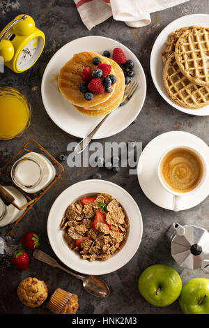 Gesundes Frühstück mit Müsli, Obst, Pfannkuchen und Waffeln über Kopf gedreht auf den Tisch Stockfoto