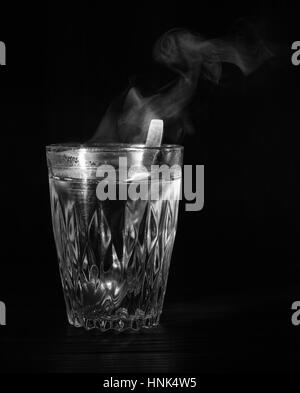 Transparente Glasschale mit Schwellen das kochende Wasser hinein. Der Dampf von oben. Schwarzer Hintergrund. Platz für Text. Stockfoto