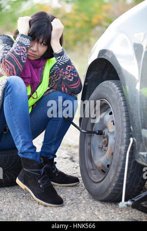 Frau, die einen Radwechsel auf ein Auto auf die leere Straße, Tiefenschärfe und kleine Schärfentiefe Stockfoto