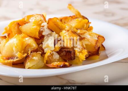 Pommes Frites mit zerschlagenen Eiern auf weißen Teller über Tisch Stockfoto