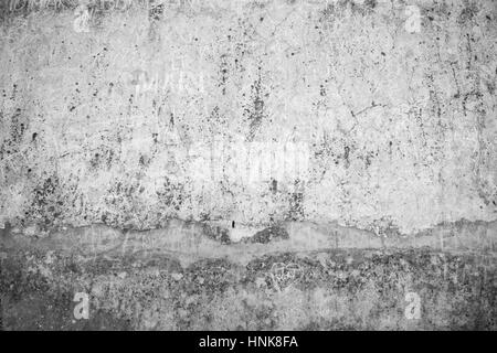 Verwitterte, Alter und rissige graue Steinmauer mit Namen zerkratzt drauf in schwarz & weiß. Stockfoto