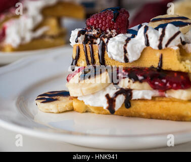 Belgische Waffeln mit Himbeeren und Sahne auf weißen Teller. Stockfoto