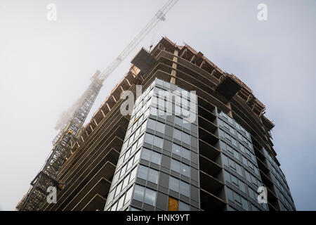 Turmdrehkran über ein Gebäude im Bau im Nebel. Stockfoto