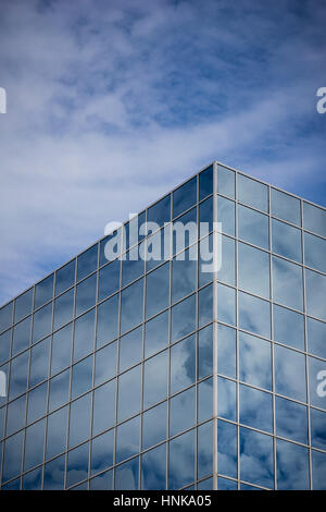 Reflexionen verursachen einen Glas-Büroturm, teilweise mit einem wolkenlos blauen Himmel zu verschmelzen. Stockfoto