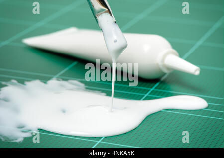 Closeup weiß Latexkleber Verschütten auf Schneidematte Stockfoto