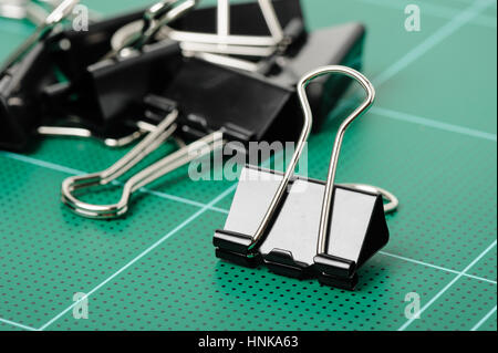 schwarze Binder Clips isoliert auf der Schneidematte Stockfoto