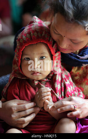 15 Monate altes Mädchen in den Armen ihrer Mutter Blick auf die Kamera, Nepal, Asien Stockfoto