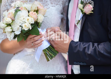 Bräutigam hält seine Bräute Hand und ein Brautstrauß Stockfoto