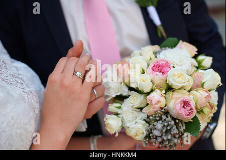 Bräutigam hält seine Bräute Hand und ein Brautstrauß Stockfoto