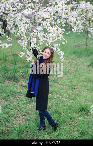 schöne glückliche junge Frau, die zu Fuß in einer blühenden Frühlingsgarten Stockfoto