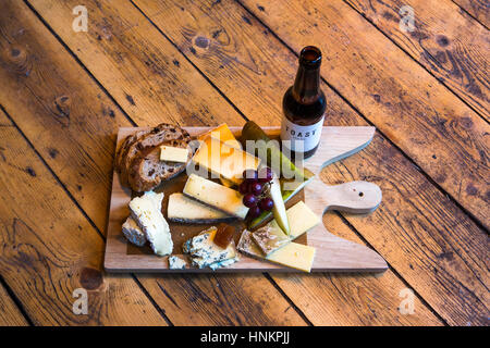 Deli Board Käseauswahl auf Holzbrett mit Flasche Bier. Stockfoto