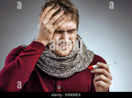 Mann leidet unter starken Kopfschmerzen. Foto von kranker Mann in Schal hielt seinen Kopf mit seinen Händen und fühlt sich Angst Stockfoto