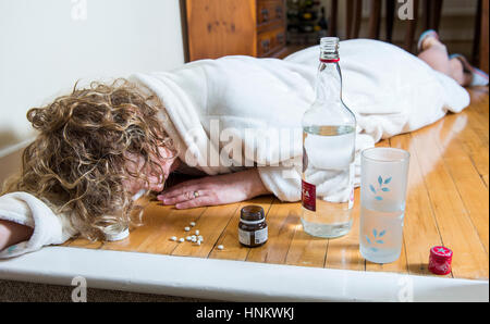 Depressiven Frau in ihren Bademantel zu Hause während des Tages, die Einnahme von Pillen und viel getrunken, sich selbst zu behandeln - Foto von Modell ausgehenden Stockfoto