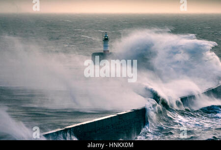 Riesige Wellen über einen Deich in der Nähe von einem Leuchtturm während eines Sturms Stockfoto