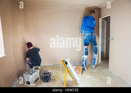 An electrician and plasterer working on the walls of a house under construction. Stockfoto