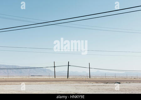 Telefonmasten und Stromleitungen in der Nähe von Trona (Kalifornien). Stockfoto