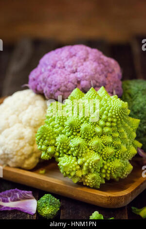 Frische Bio weiße und violette Blumenkohl, Brokkoli, Romanesco in Holzschale Stockfoto