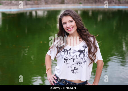 lächelnde junge Frau auf dem Hintergrund des Sees im park Stockfoto