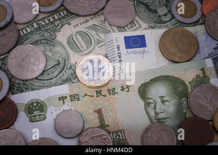 British Pound Münze gegen den Hintergrund der Währungen einschließlich Yuan, Dollar und Euro Stockfoto