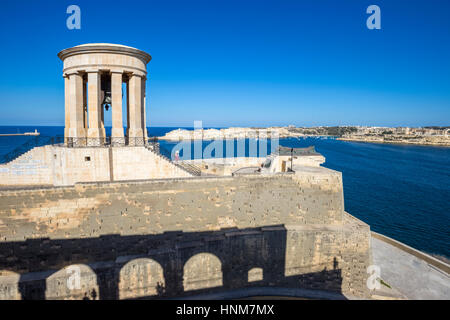 Valletta, Malta - Belagerung Bell War Memorial an den Grand Harbor von Valletta mit Touristen und klaren, blauen Himmel Stockfoto