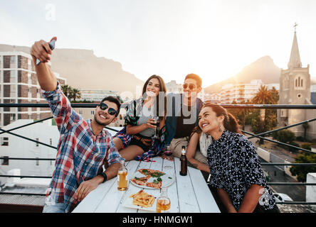 Gruppe von Freunden mit einer Party auf dem Dach ein Selbstporträt zu machen. Glücklich Jugendlichen Selbstbildnis während Party. Stockfoto