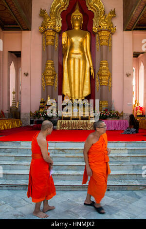 Buddhistische Mönche zu Fuß in eine goldene Buddhastatue in Bangkok, Thailand. Stockfoto