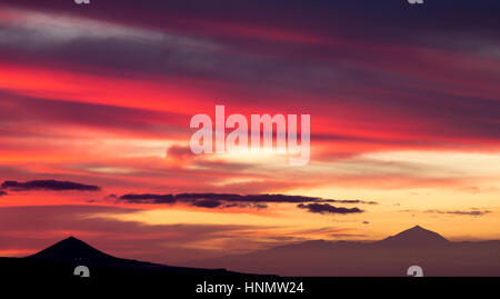 Las Palmas, Gran Canaria, Kanarische Inseln, Spanien. 14. Februar 2017. Wetter: Ein atemberaubender Sonnenuntergang auf Gran Canaria als den Himmel explodiert mit Farbe über den Teide, (rechts) ca. 50 Meilen entfernt auf benachbarte Teneriffa. El Teide ist Spaniens höchsten Berg (3.718 m) und der drittgrößte Vulkan der Welt. Der vulkanische Berg auf der linken Seite ist Pico de Galdar (400 m) an der Nordküste von Gran Canaria. Bildnachweis: ALAN DAWSON/Alamy Live-Nachrichten Stockfoto