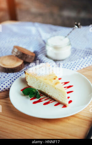 Dreieck-Käse-Kuchen im Café. Auf einem Holztisch Stockfoto