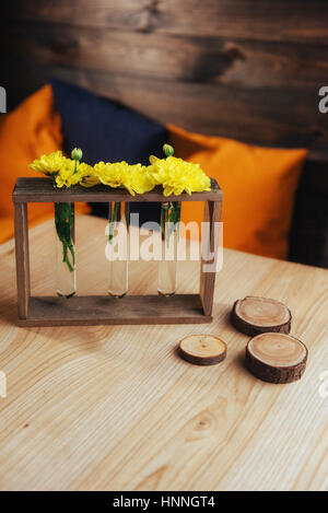 Leuchtend gelben Margeriten in einer Glasvase auf Holzschwert Stockfoto