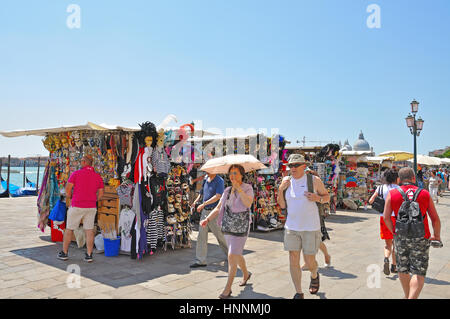 Touristen und Straßenverkäufer mit Souvenirs am Hafen von Venedig, Italien Stockfoto