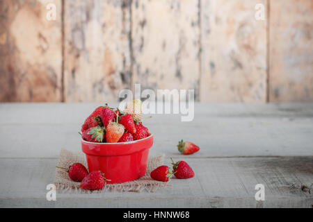 Erdbeeren in rote Tasse auf dem alten Holz. Stockfoto