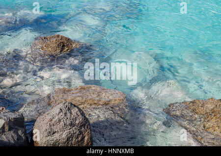 Steinen und transparent türkisfarbenes Wasser, ripple auf Oberfläche Stockfoto