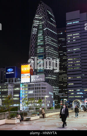 TOKYO, JAPAN - ca. April 2013: Building of Mode Gakuen Cocoon Tower ist im Stadtteil Nishi-Shinjuku in Shinjuku in der Nacht. Die Menschen gehen im footb Stockfoto