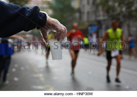 Ein freiwilliger bietet eine Tasse Wasser Läufer beim Marathon in die Innenstadt. Stockfoto