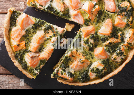 Tasty geschnittene Bohnenkraut Quiche mit Lachs und Spinat, close-up auf dem Tisch. horizontale Ansicht von oben Stockfoto