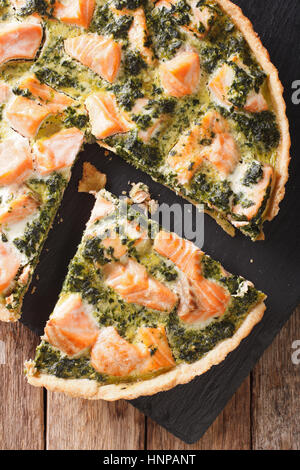 Quiche mit Lachs, Spinat und Sahne close-up auf dem Tisch geschnitten. vertikale Ansicht von oben Stockfoto