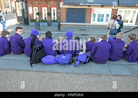 Rückansicht einer Gruppe von Grundschulkindern in lila Uniformen sitzen in der Nähe des Globe Theatre auf Bankside in South London UK KATHY DEWITT Stockfoto