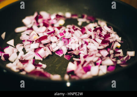 gehackte rote Zwiebel in einer Pfanne erhitzen Stockfoto