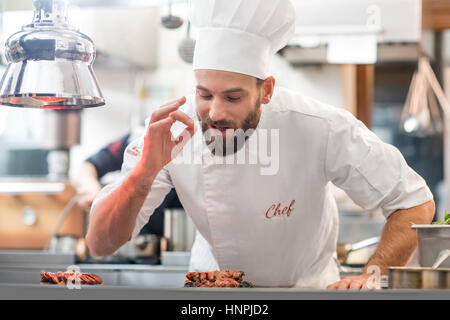 Porträt von Chef-Koch in Uniform mit schwächeln köstliches Gericht in der Restaurantküche Stockfoto