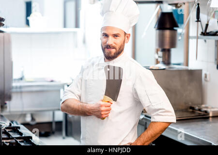 Porträt von Chef-Koch in Uniform mit Messern in der Restaurantküche Stockfoto