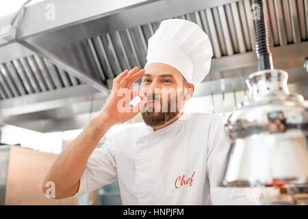 Porträt einer schönen Chef-Koch in uniform zeigt köstliche Zeichen in der Restaurantküche Stockfoto